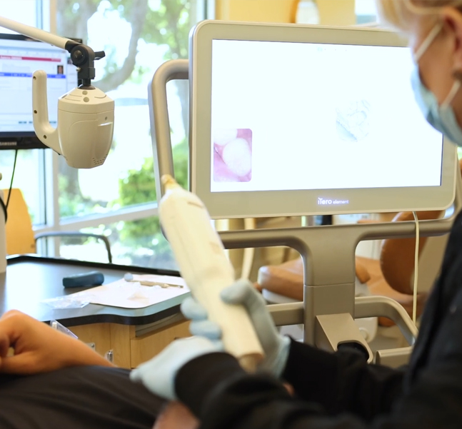 Orthodontist examining dental scan on monitor during patient consultation in bright, modern office.