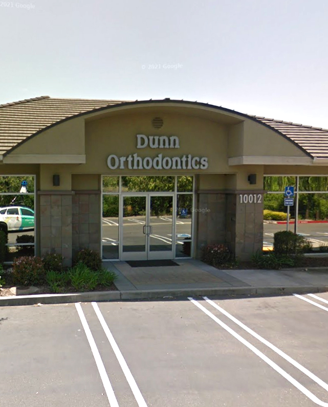 Exterior view of Dunn Orthodontics office building with entrance and signage in daytime setting.