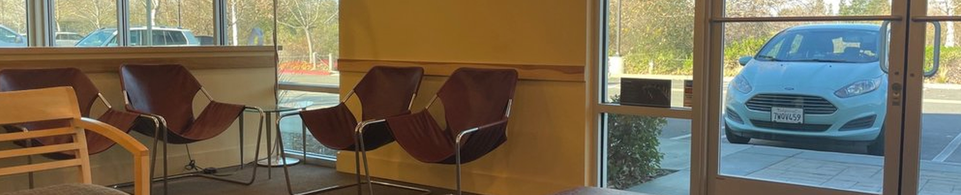 Modern orthodontic office reception area with comfortable seating and blue car visible through window.